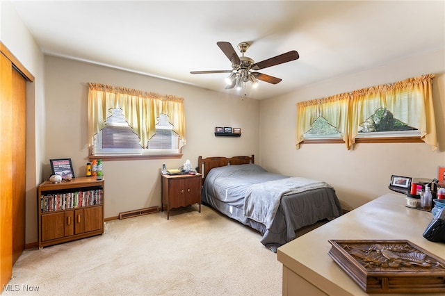 bedroom featuring ceiling fan, light colored carpet, a closet, and multiple windows