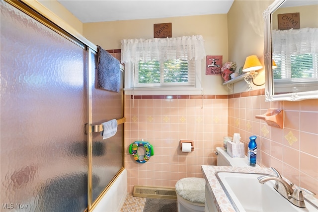 full bathroom with tile walls, bath / shower combo with glass door, toilet, and plenty of natural light