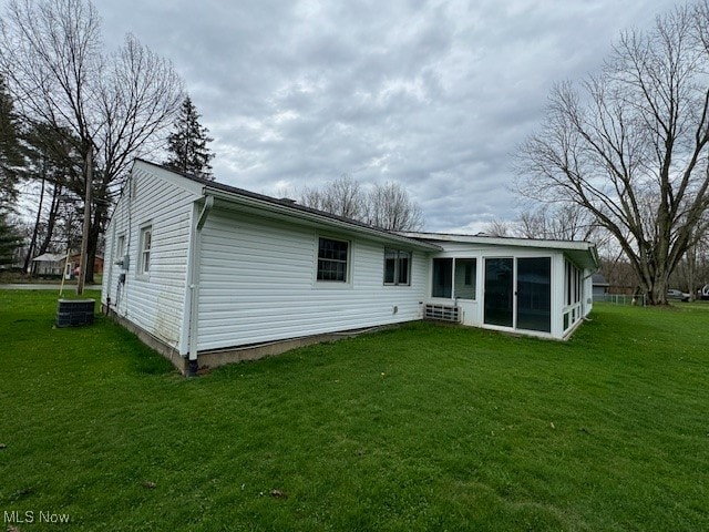 rear view of property featuring a lawn and a sunroom