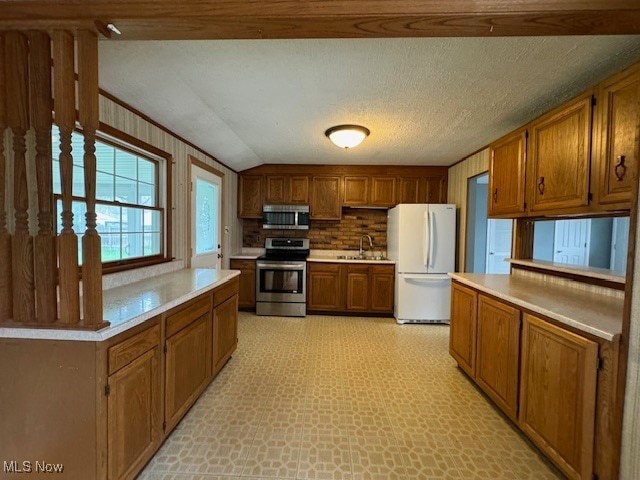 kitchen with a textured ceiling, stainless steel appliances, sink, and decorative backsplash