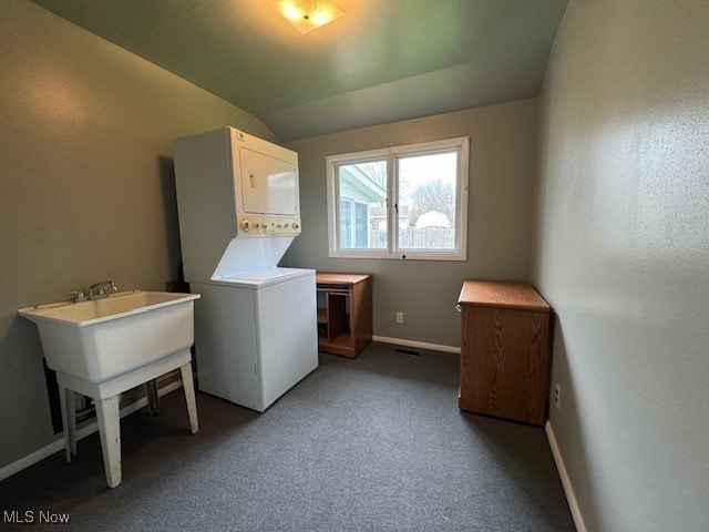 clothes washing area featuring dark carpet and stacked washer / dryer