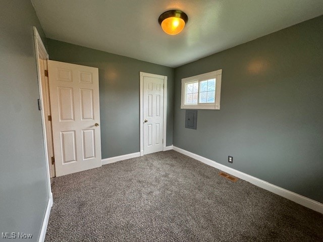 unfurnished bedroom featuring electric panel, a closet, and carpet floors