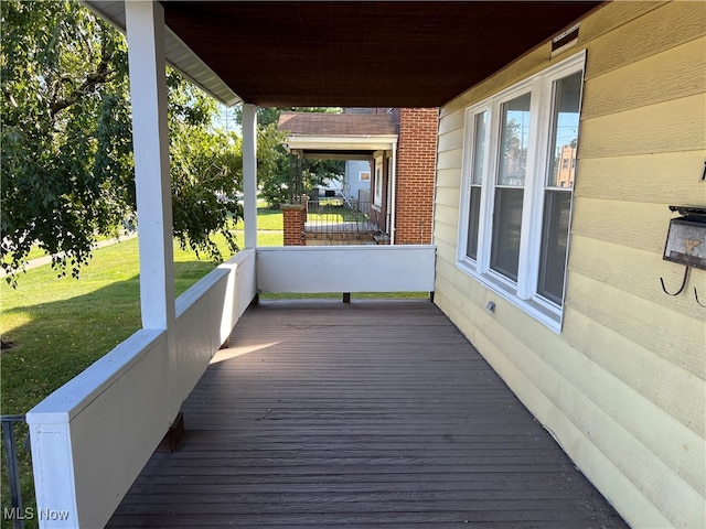 wooden deck with a lawn and a porch