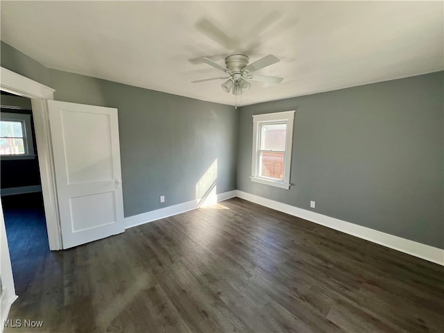 empty room with a healthy amount of sunlight, dark hardwood / wood-style flooring, and ceiling fan