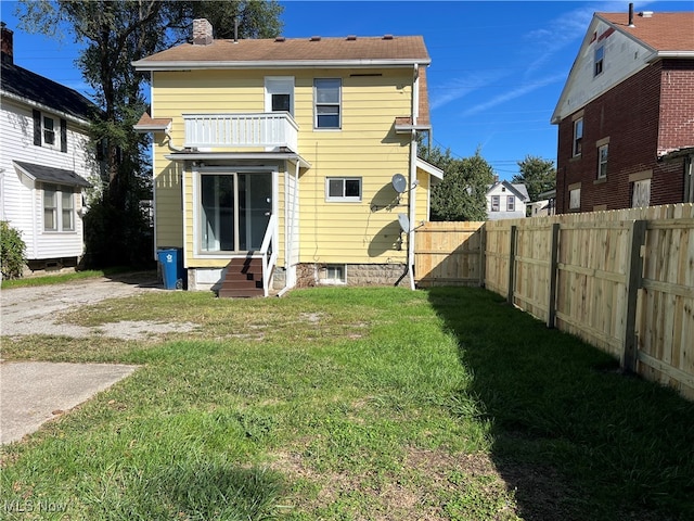 back of property with a lawn and a balcony