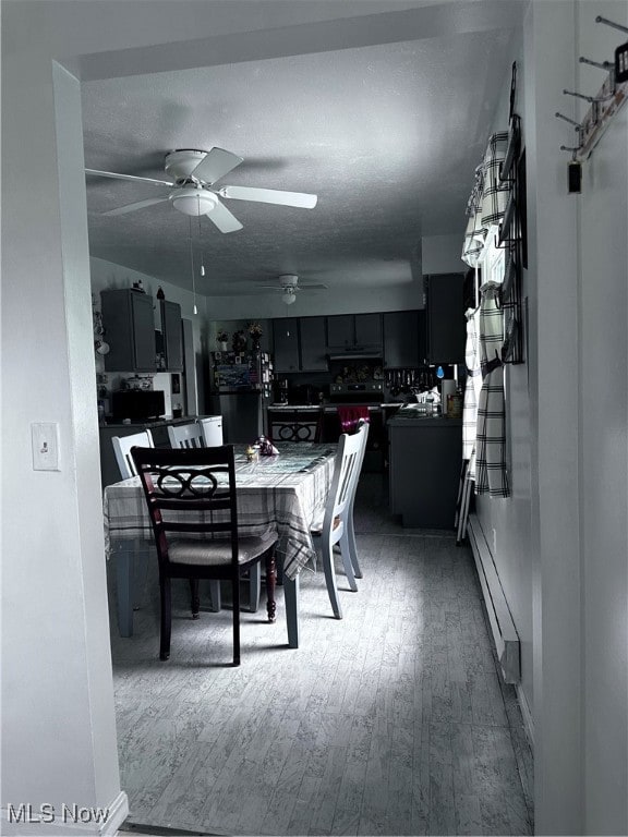 dining area featuring a baseboard heating unit, wood-type flooring, ceiling fan, and a textured ceiling