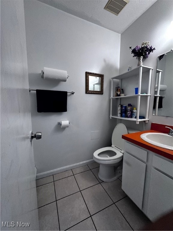 bathroom with vanity, tile patterned flooring, toilet, and a textured ceiling