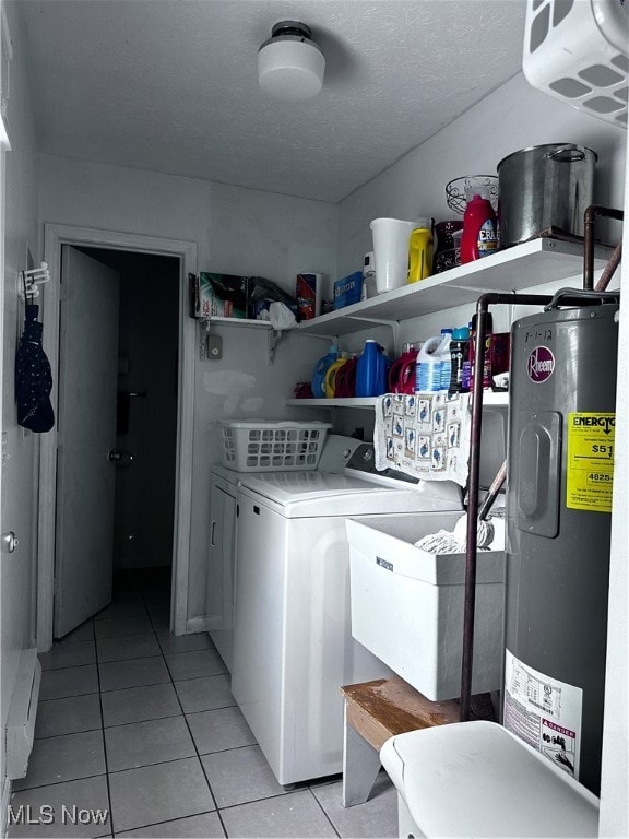 washroom with a textured ceiling, light tile patterned floors, independent washer and dryer, and electric water heater