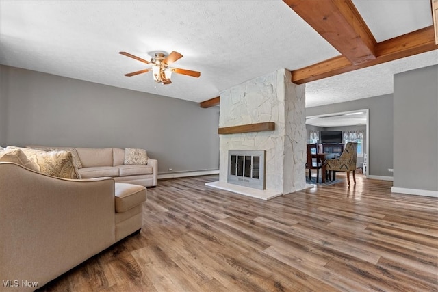 living room with a fireplace, baseboard heating, a textured ceiling, ceiling fan, and hardwood / wood-style floors