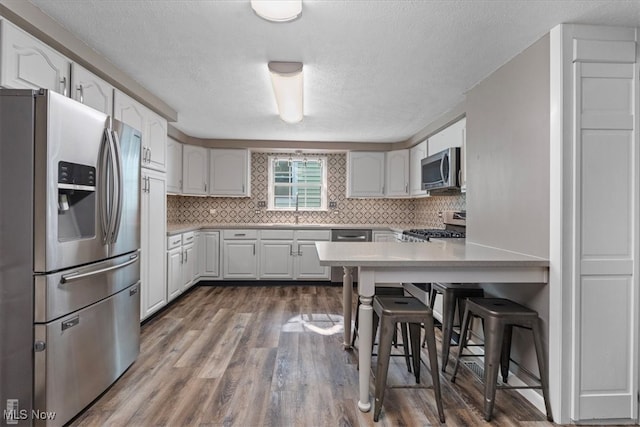 kitchen featuring stainless steel appliances, white cabinetry, a textured ceiling, and dark wood-type flooring