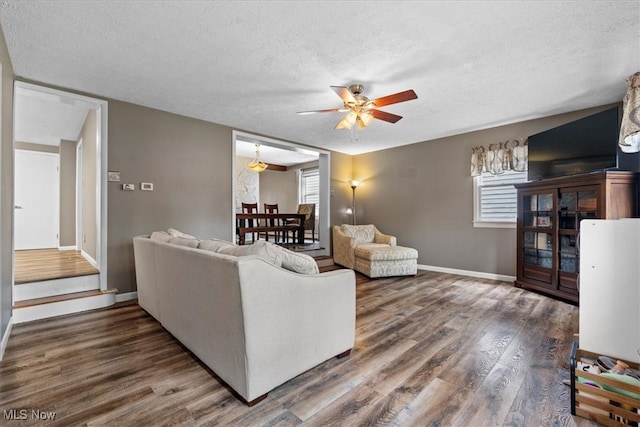 living room featuring a textured ceiling, dark hardwood / wood-style floors, and ceiling fan