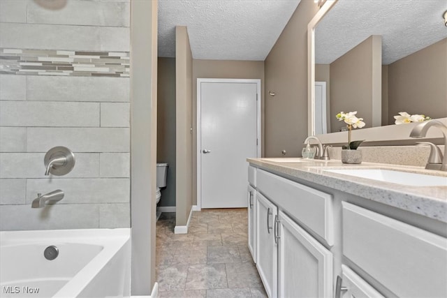 bathroom with a tub, toilet, vanity, and a textured ceiling