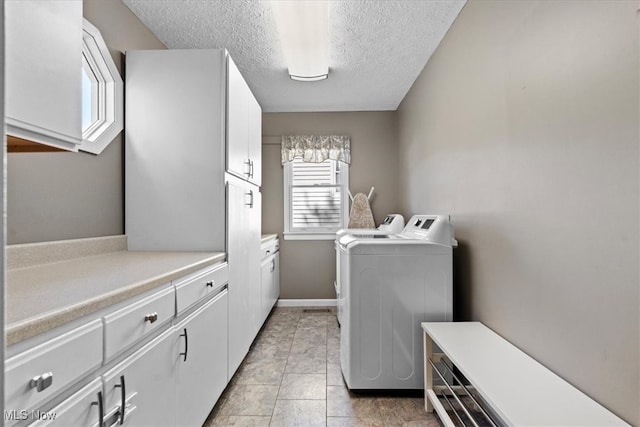 washroom with cabinets, a textured ceiling, independent washer and dryer, and light tile patterned flooring