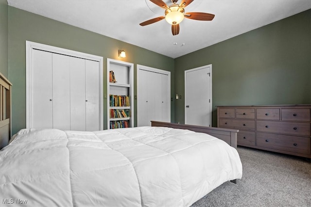 bedroom featuring ceiling fan, light colored carpet, and multiple closets