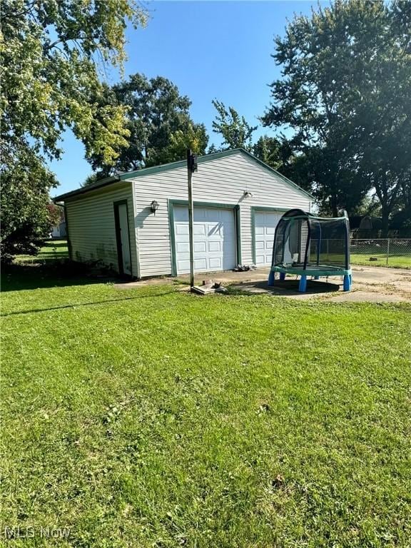 garage featuring a trampoline and a lawn