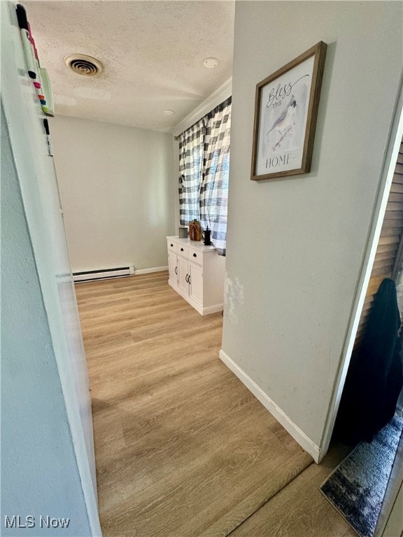 hallway featuring a baseboard heating unit, a textured ceiling, and light hardwood / wood-style floors