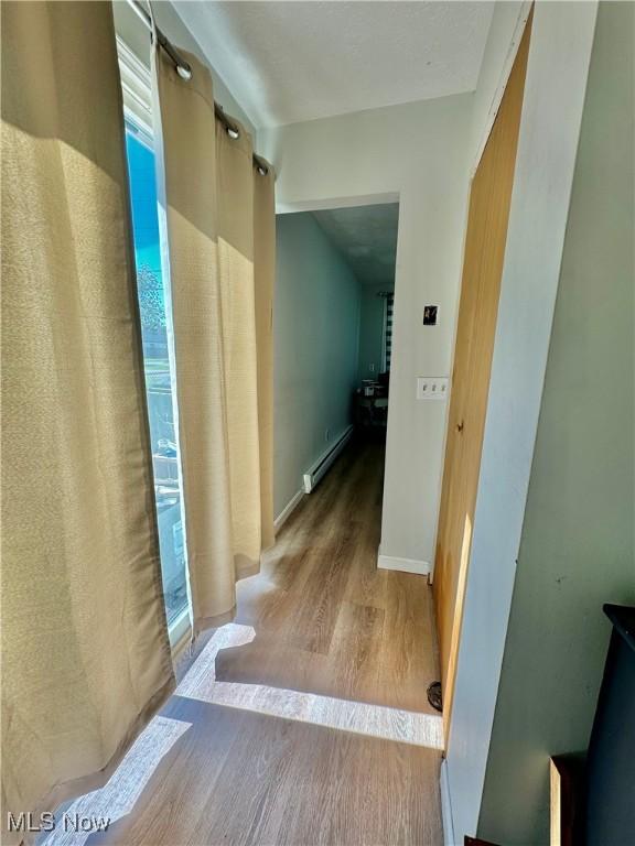 corridor with a baseboard heating unit and light wood-type flooring