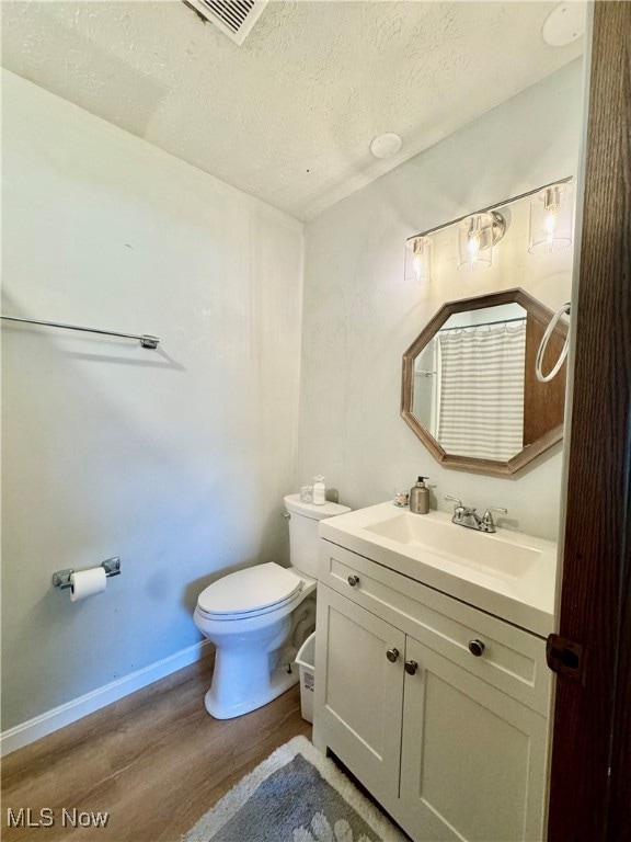 bathroom with vanity, hardwood / wood-style flooring, a textured ceiling, and toilet