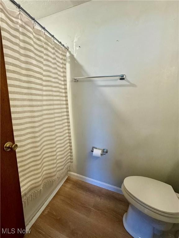 bathroom featuring walk in shower, wood-type flooring, and toilet