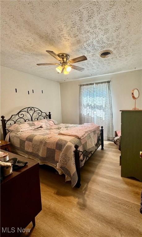 bedroom with ceiling fan and a textured ceiling