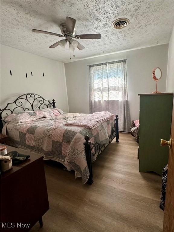 bedroom featuring a textured ceiling, ceiling fan, and light hardwood / wood-style floors