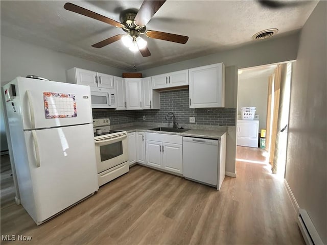 kitchen with sink, white appliances, white cabinetry, washer / clothes dryer, and a baseboard radiator