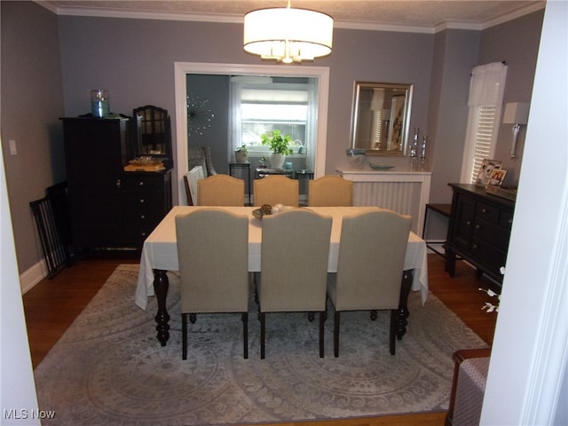 dining area with ornamental molding, a notable chandelier, and hardwood / wood-style floors