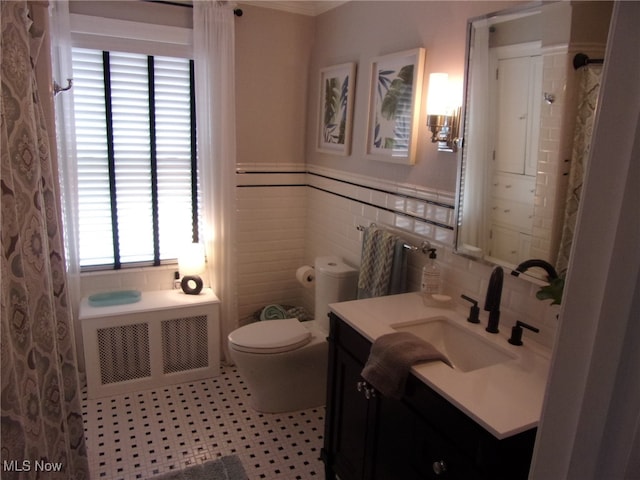 bathroom featuring vanity, toilet, radiator, and plenty of natural light