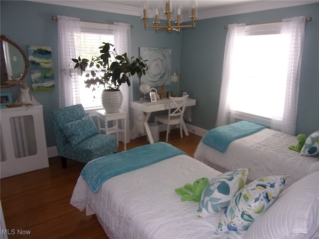 bedroom with wood-type flooring, crown molding, and an inviting chandelier