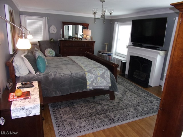 bedroom with light hardwood / wood-style floors, ornamental molding, and a chandelier