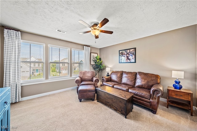 living room with a textured ceiling, ceiling fan, and light colored carpet