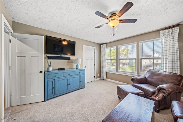 living room featuring ceiling fan, light colored carpet, and a textured ceiling