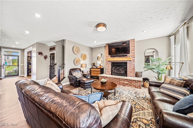 living room with light wood-type flooring, a textured ceiling, and a fireplace