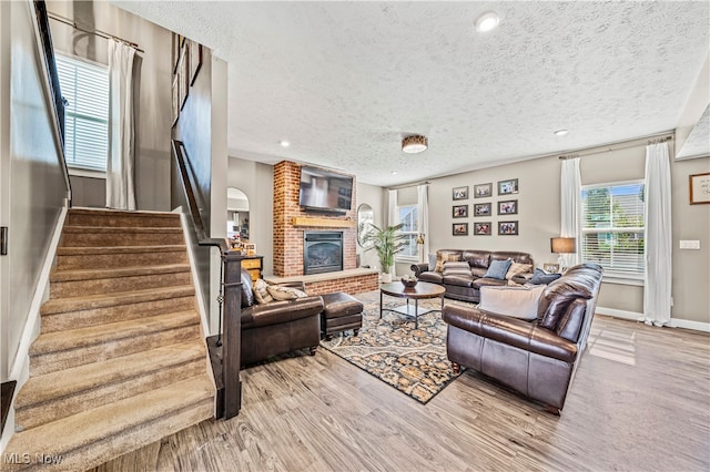 living room with light hardwood / wood-style flooring, a textured ceiling, and a fireplace