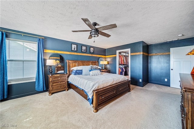 carpeted bedroom featuring a textured ceiling, a spacious closet, ceiling fan, and a closet