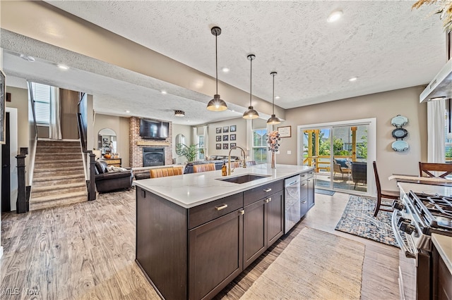 kitchen featuring a textured ceiling, a center island with sink, dark brown cabinets, and sink