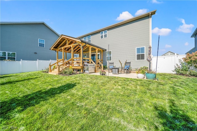 back of house with a yard, a wooden deck, and a patio area