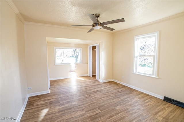 spare room featuring a textured ceiling, wood-type flooring, ornamental molding, and ceiling fan