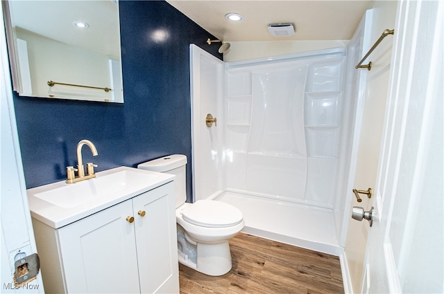 bathroom featuring lofted ceiling, a shower, hardwood / wood-style floors, vanity, and toilet