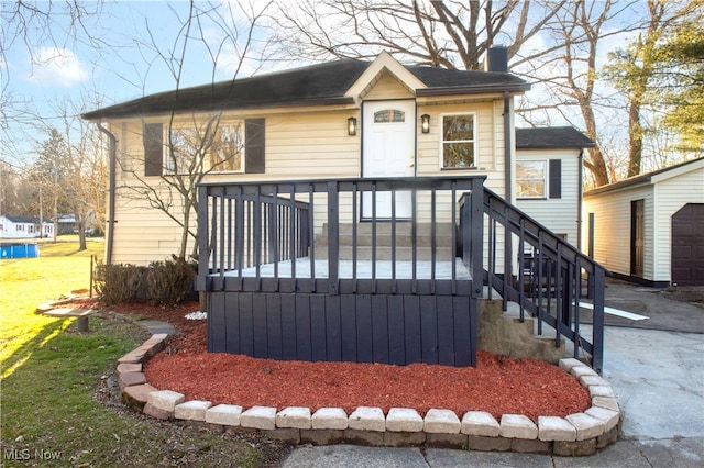 view of front of property with a front yard, a garage, an outdoor structure, and a deck