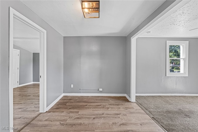 spare room featuring light hardwood / wood-style flooring and a textured ceiling