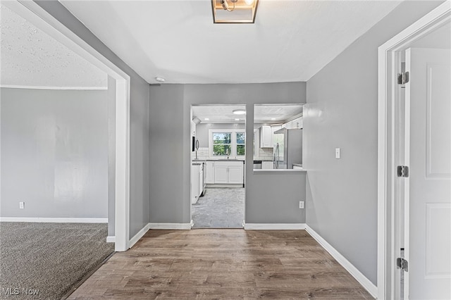 hallway with a textured ceiling and hardwood / wood-style flooring