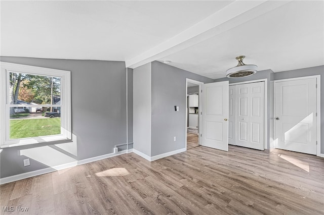 empty room featuring vaulted ceiling with beams and light hardwood / wood-style floors