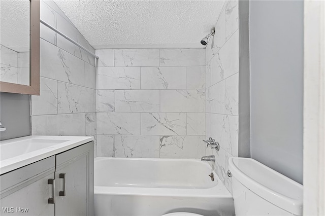 full bathroom featuring a textured ceiling, vanity, toilet, and tiled shower / bath