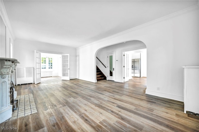 unfurnished living room featuring hardwood / wood-style flooring and crown molding