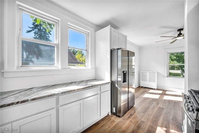 kitchen with ceiling fan, white cabinetry, appliances with stainless steel finishes, light stone countertops, and light hardwood / wood-style floors