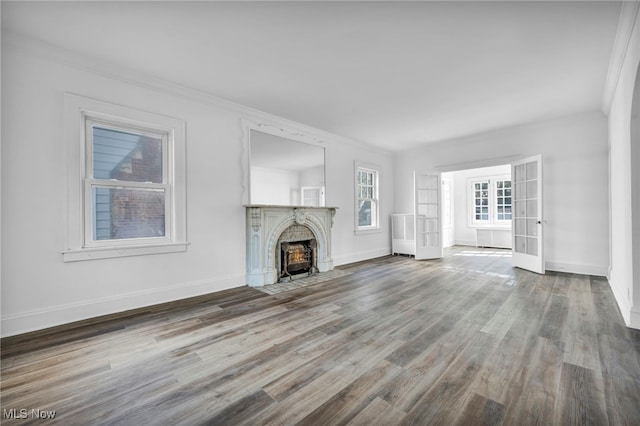 unfurnished living room with ornamental molding, wood-type flooring, and french doors