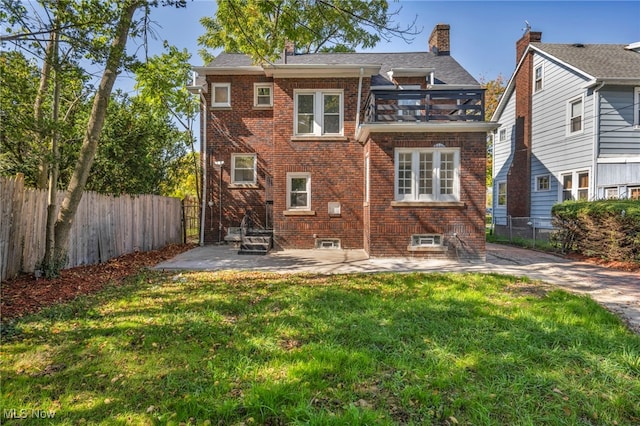 rear view of house featuring a balcony, a yard, and a patio