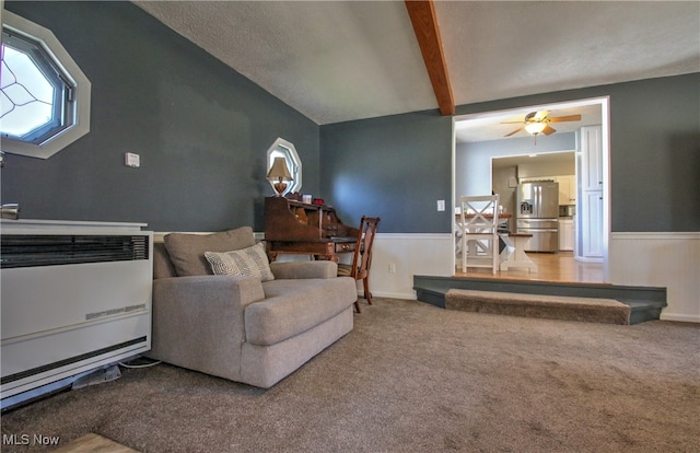 living room featuring ceiling fan, vaulted ceiling with beams, carpet flooring, heating unit, and a textured ceiling