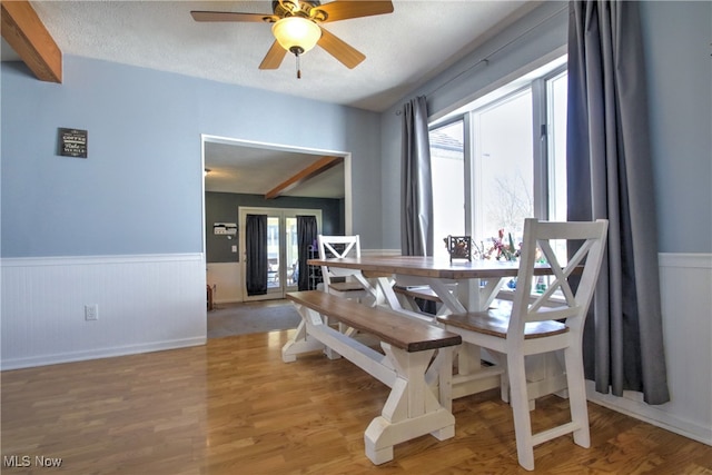 dining room featuring a textured ceiling, hardwood / wood-style floors, beamed ceiling, and ceiling fan